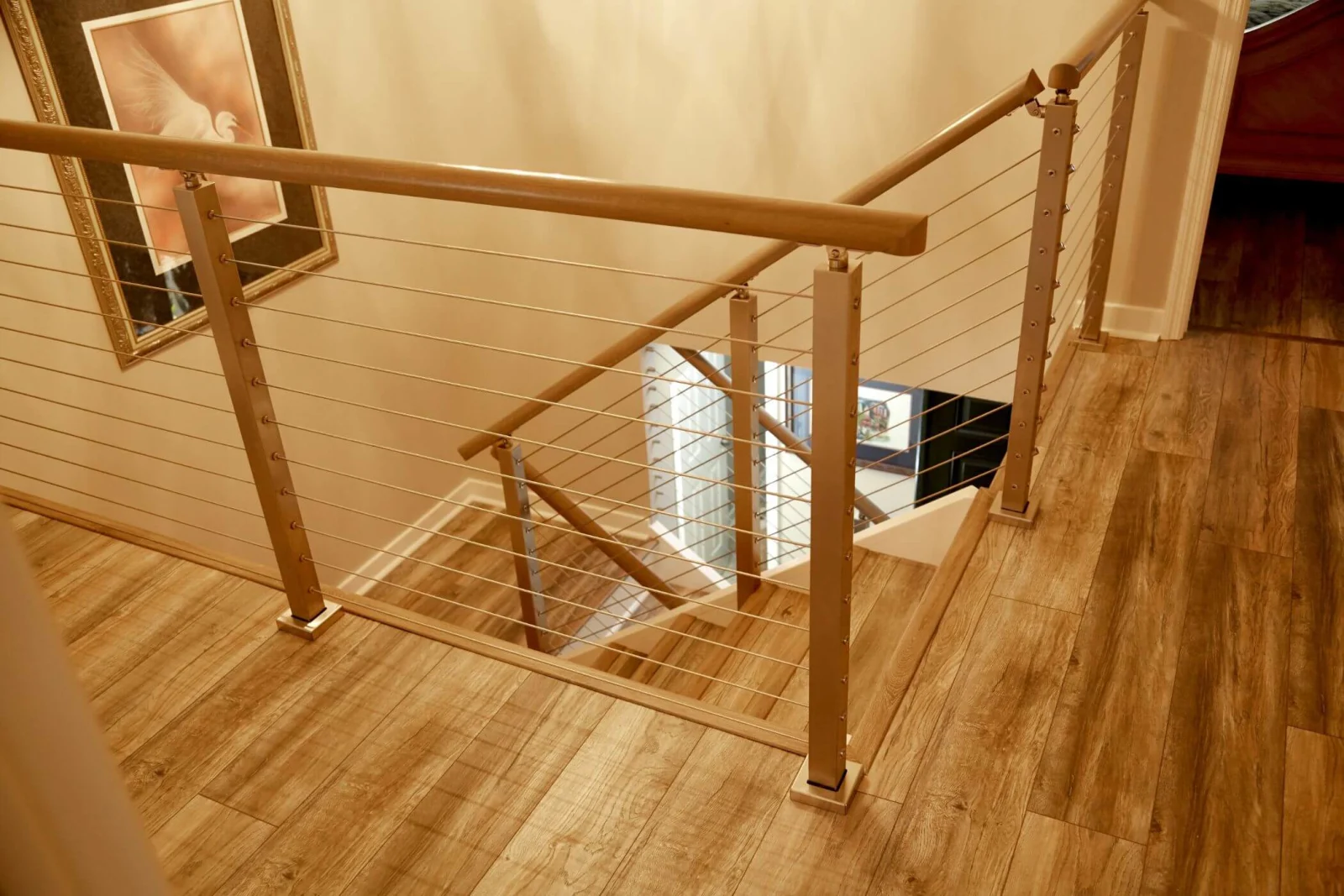 Looking down at a landing where cable railing turns the corner above the stair
