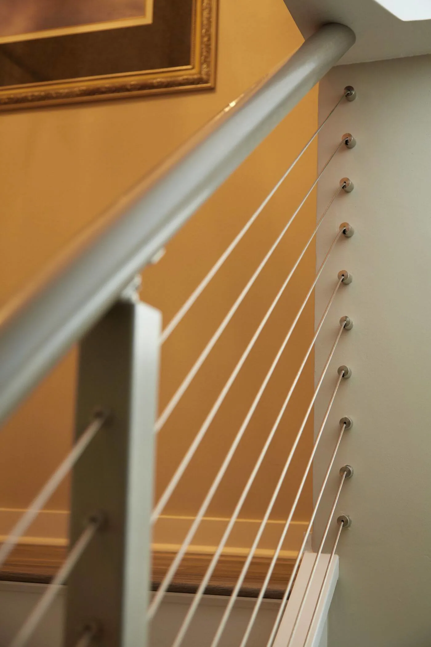 Close view of a rounded metal handrail with cables angling up the stair