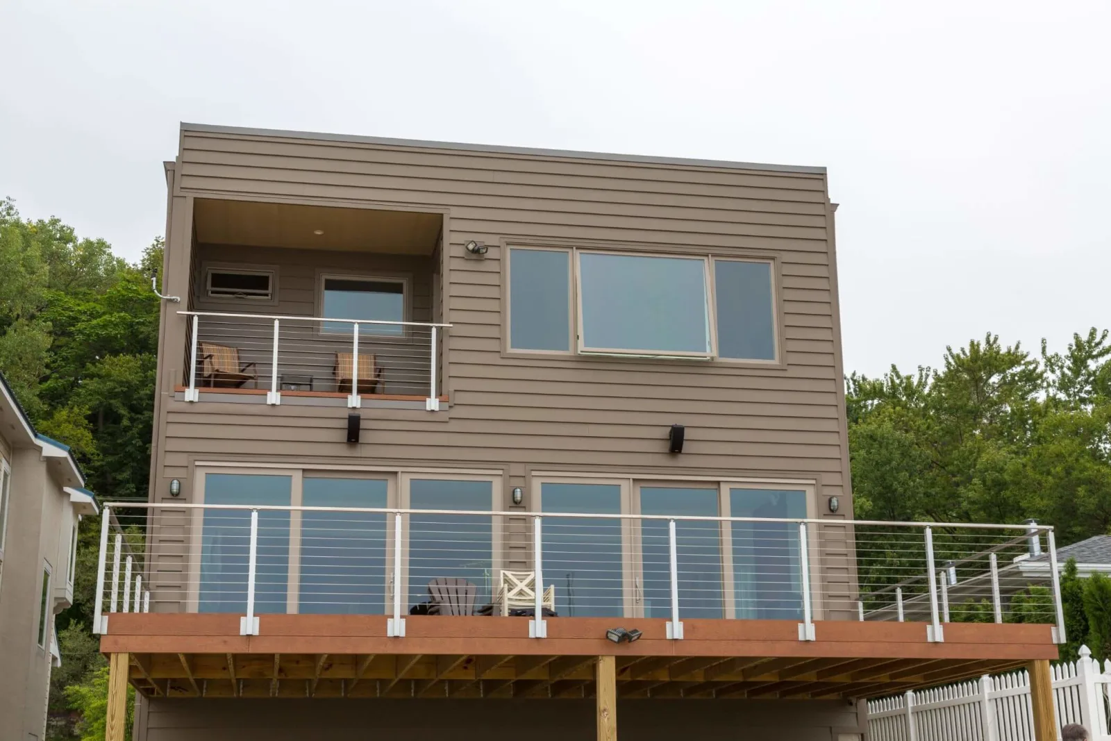 Two levels of cable railing on a lakeside home's deck and upper balcony