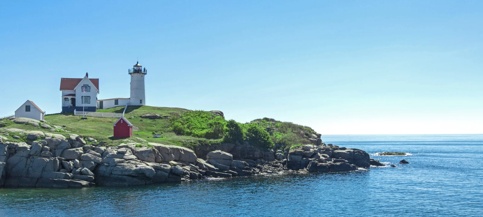 Lighthouse on a rocky headland above the ocean under a clear sky