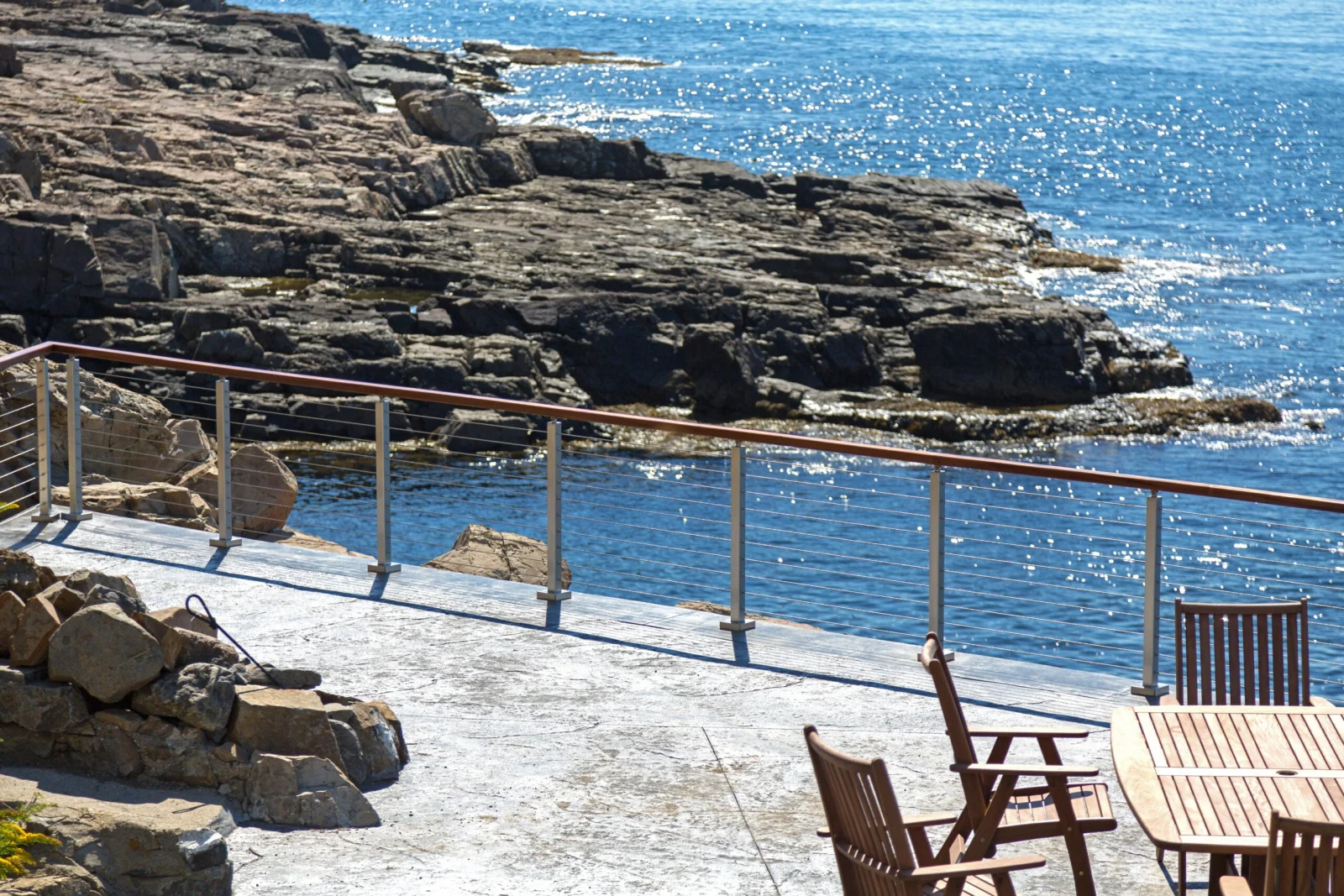 Patio seating beside a cable run that follows the rocky shoreline edge