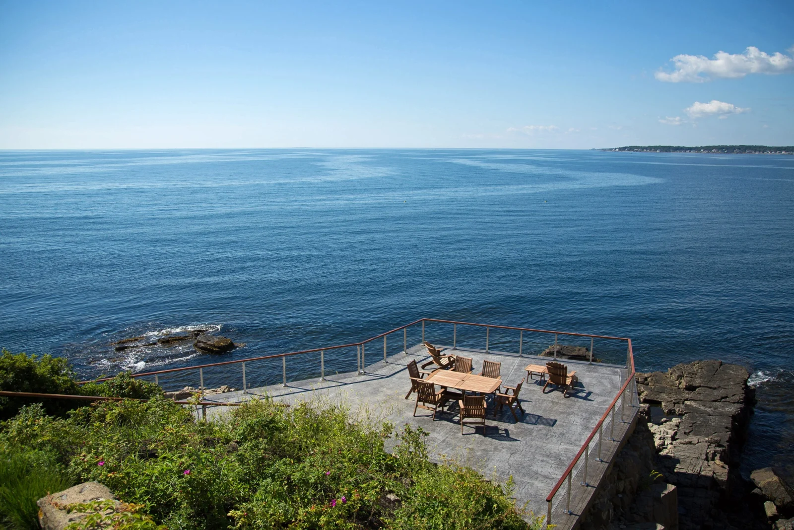 Overhead view of a clifftop patio ringed with railing above the open ocean