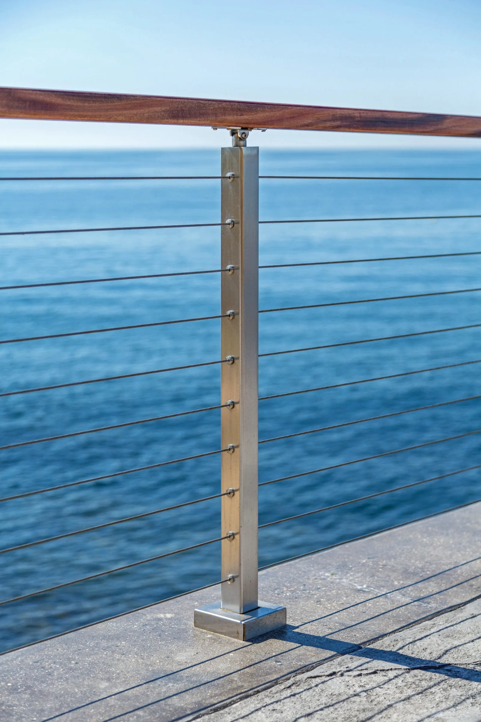Single stainless post and wood top rail at the edge of a concrete patio