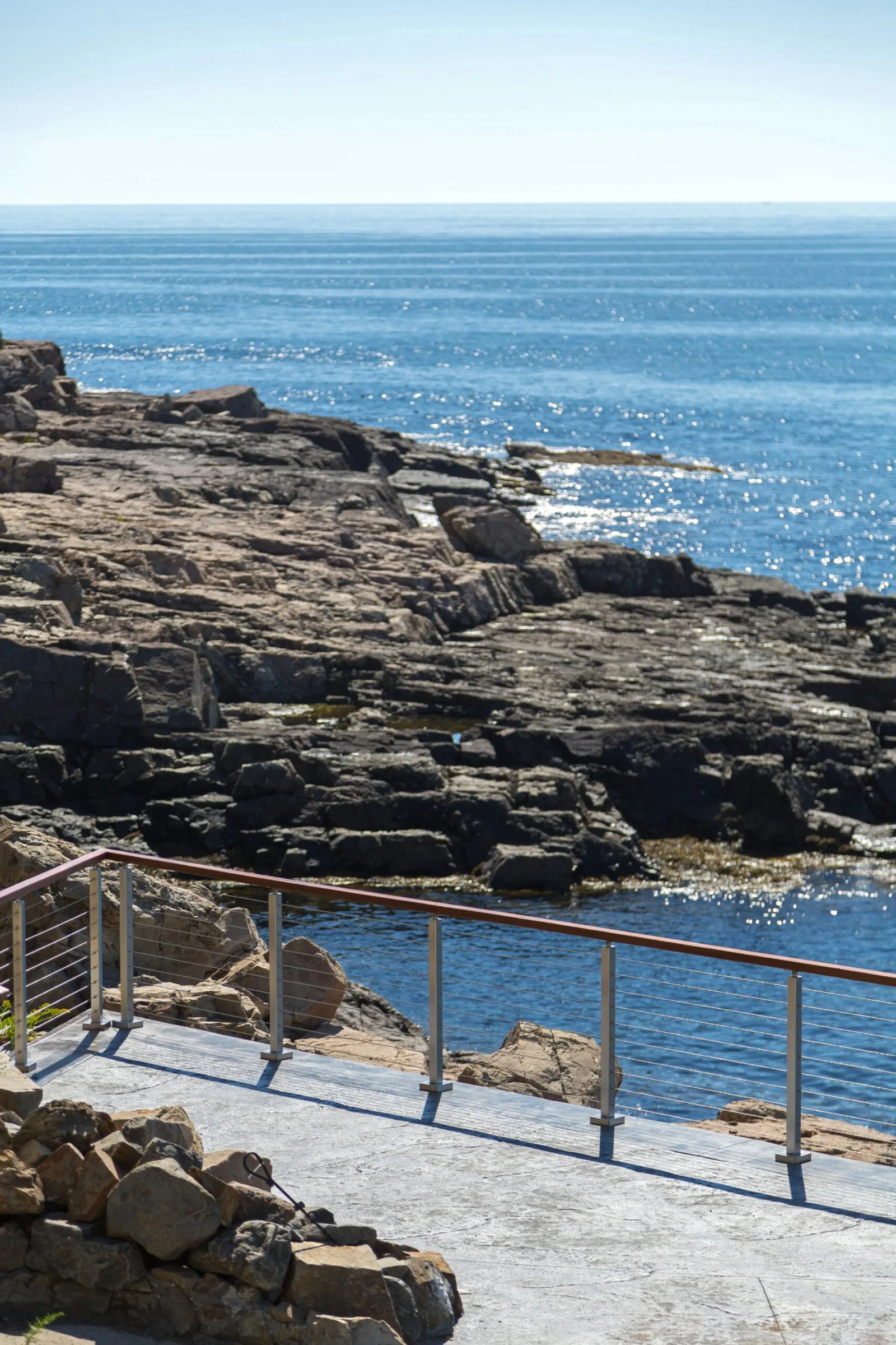 Railing corner on the patio with boulders and open sea filling the view