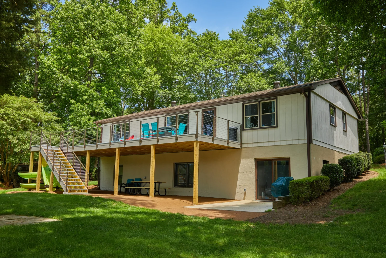 Elevated deck wrapping a lakeside cottage with cable railing along its full length