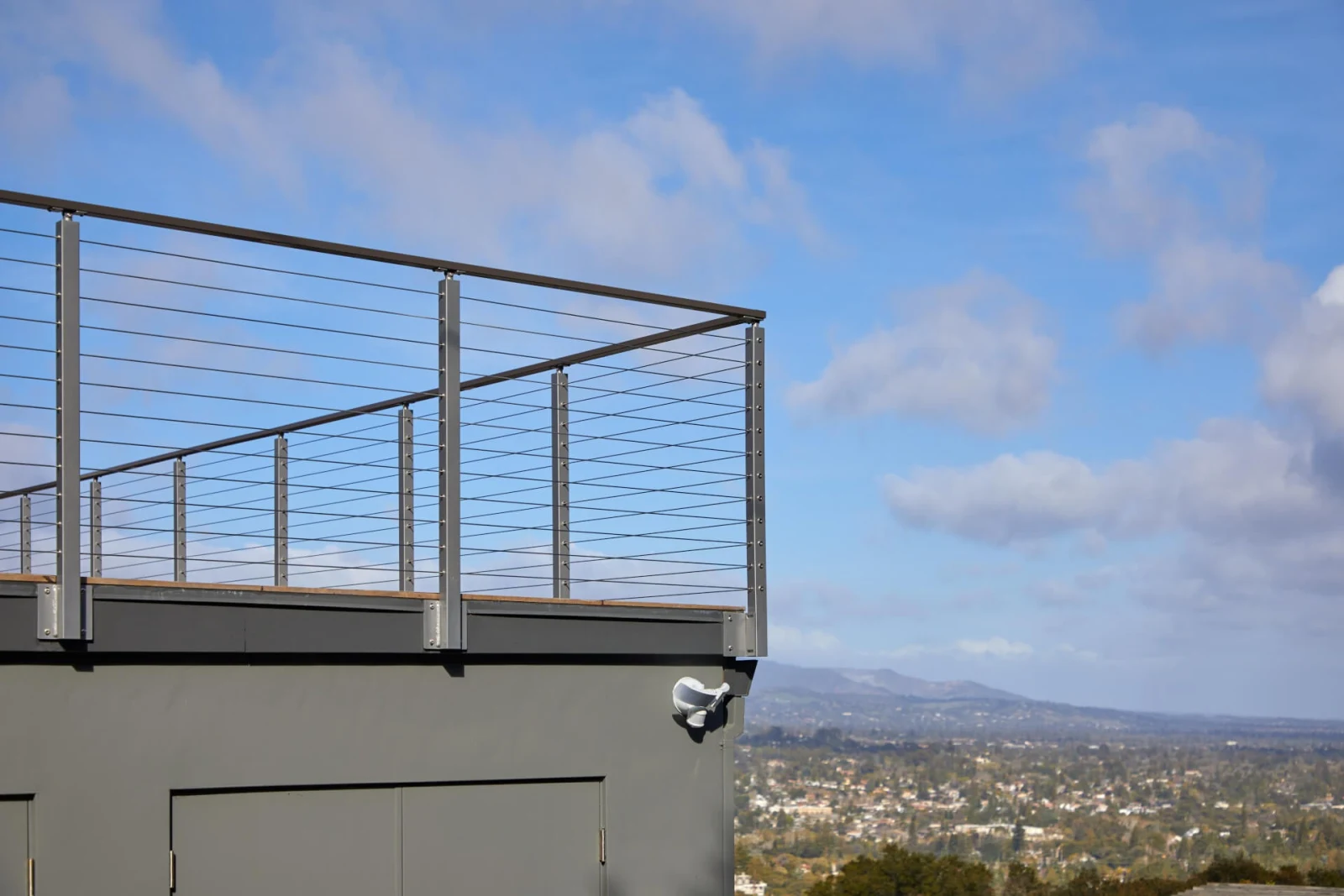 Roof parapet railing seen from below against open sky and clouds
