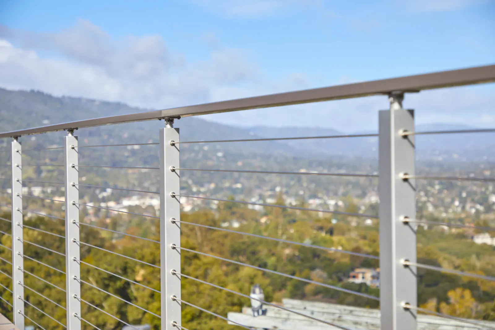 Close view of cable fittings threaded through slim posts above the city