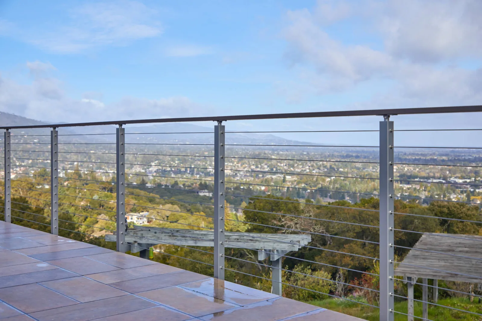 Wide terrace run with slim posts and a dark top rail above the valley