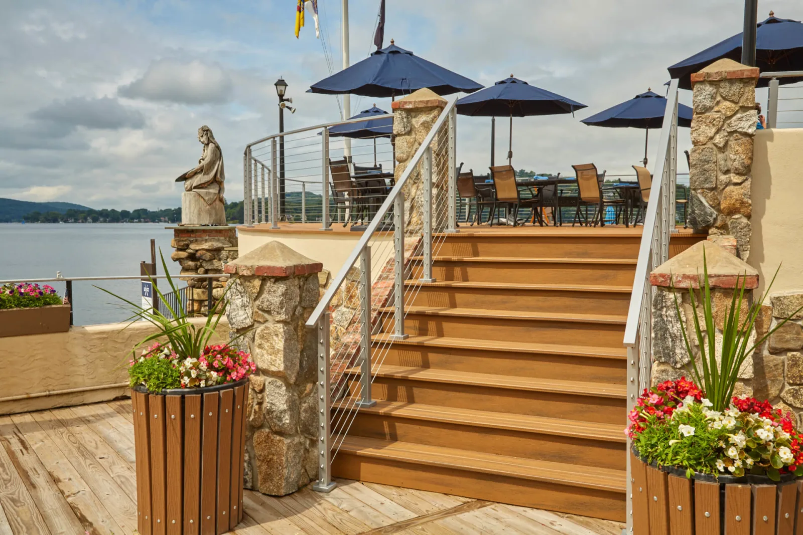 Stairs rising from a boardwalk to a lakeside patio set with umbrellas