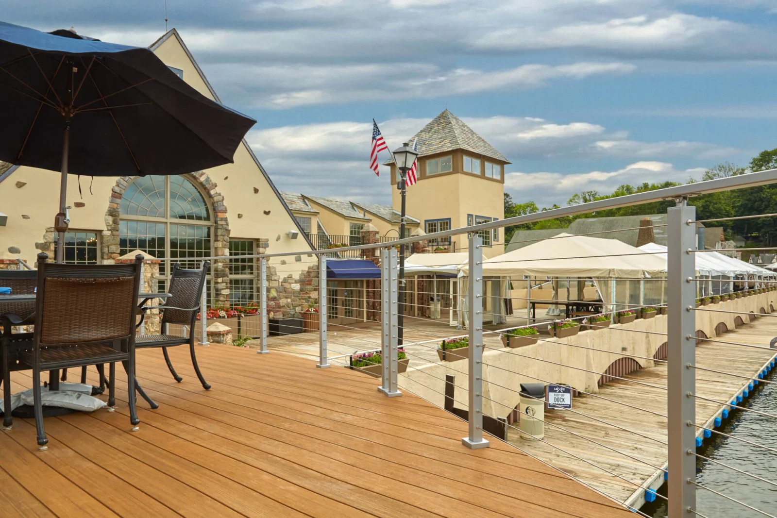 Deck railing along a dock with the restaurant and flagpole behind