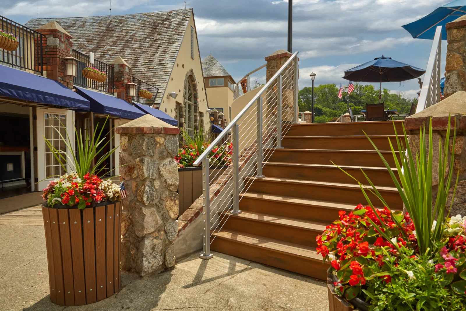 Cable railing flanking wide wood stairs in a stone-walled restaurant courtyard