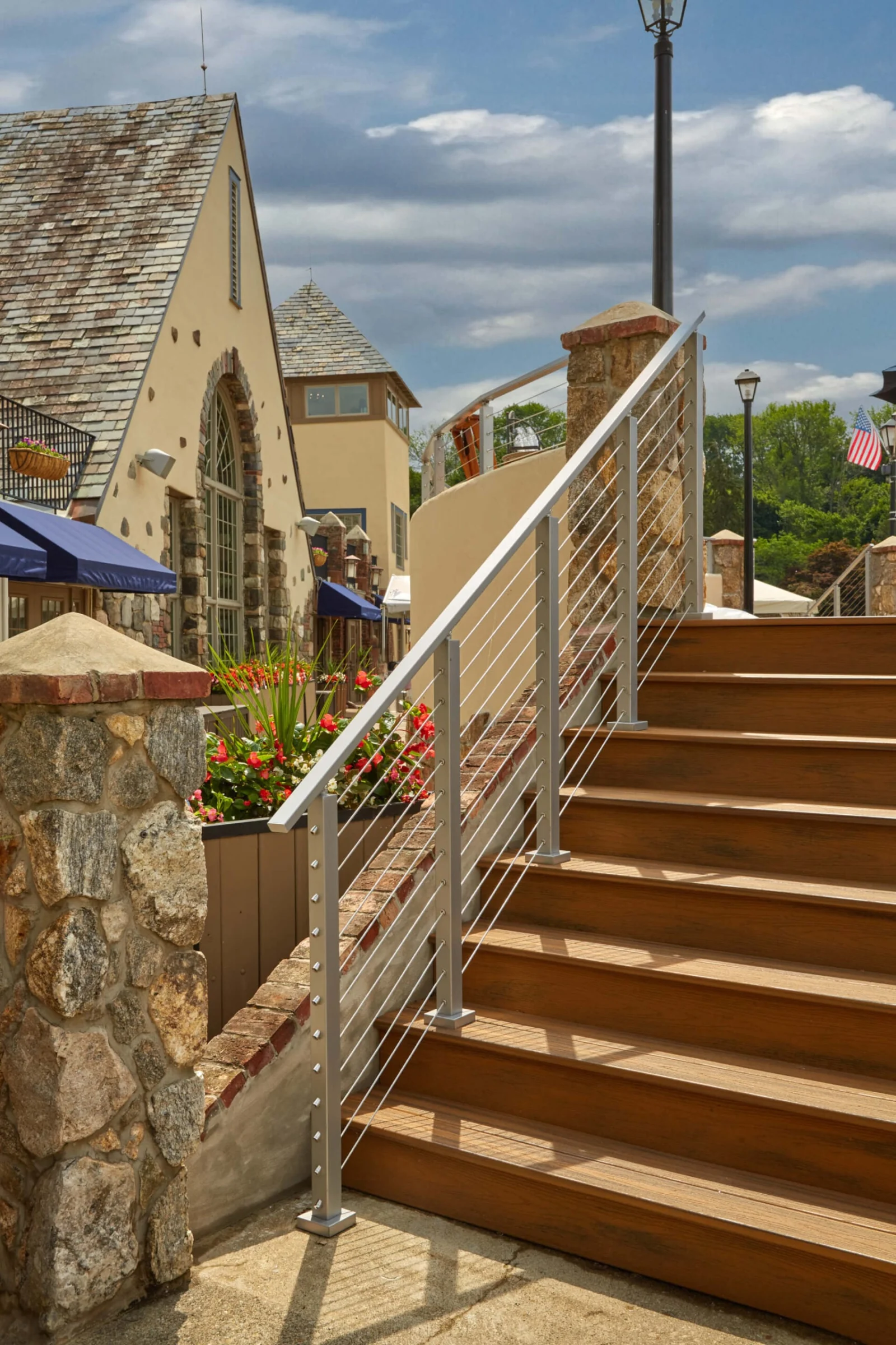 Stair railing climbing beside a stone pier toward an upper dining deck