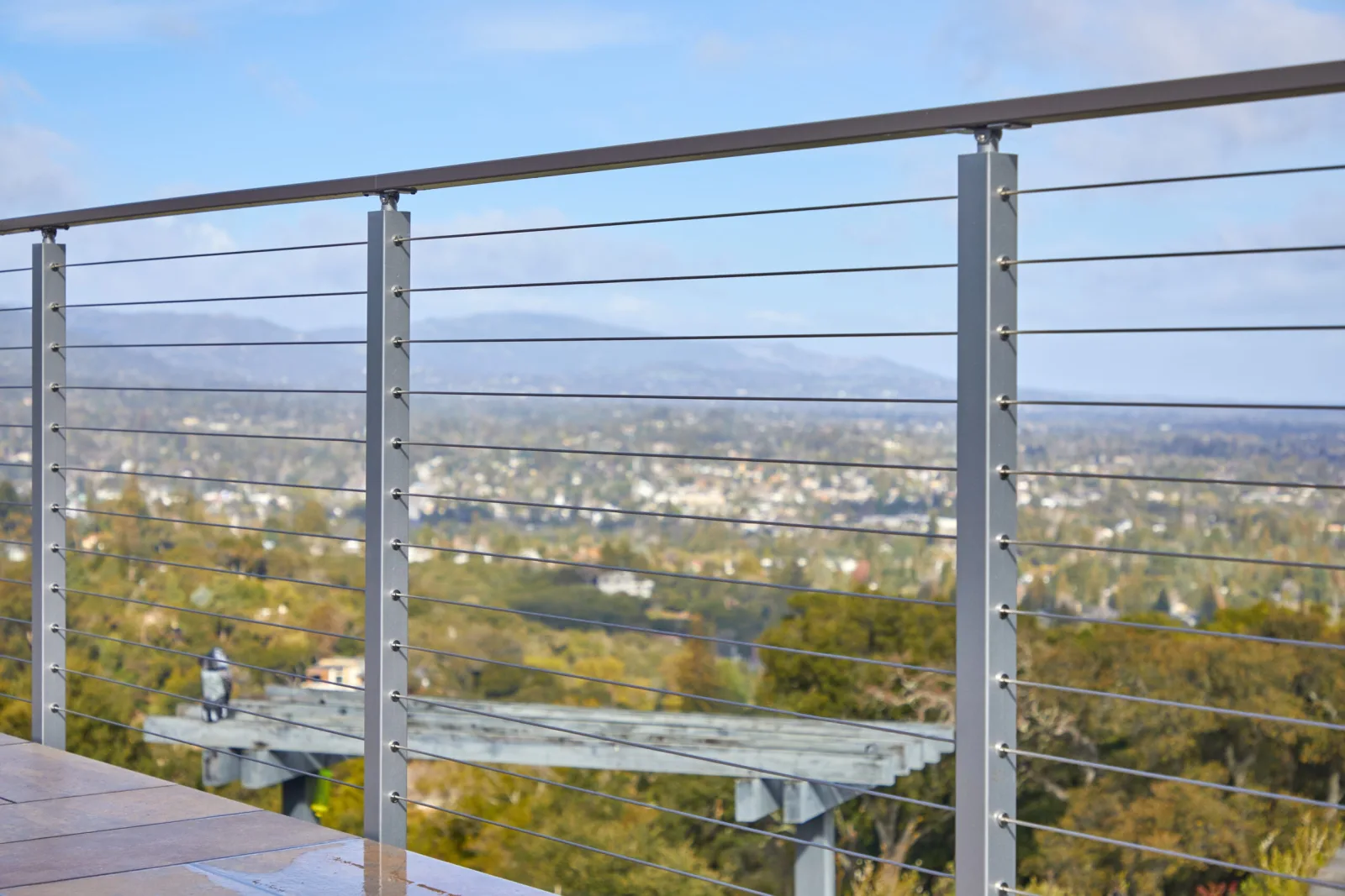 Valley panorama seen through horizontal cables from a paved terrace