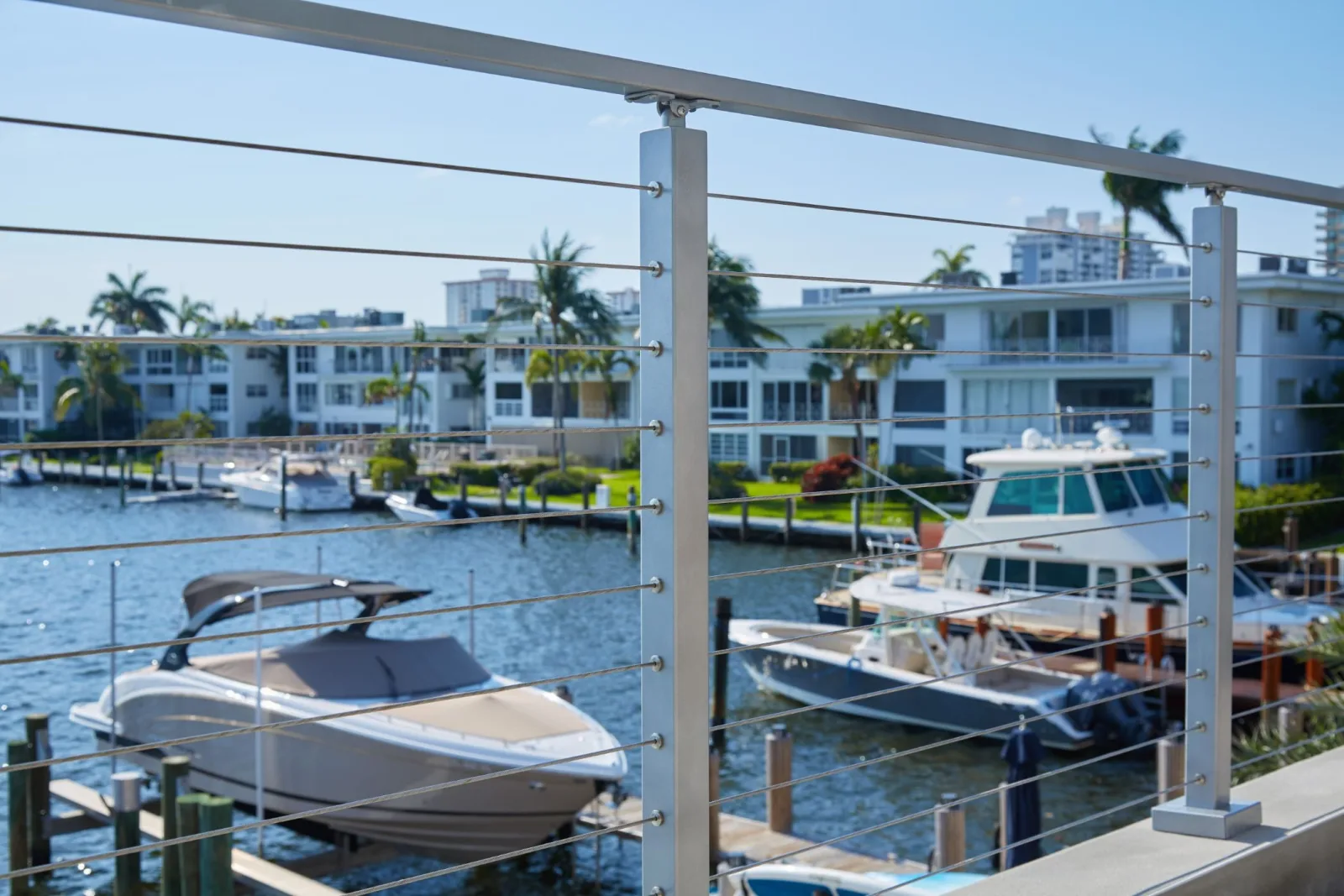 Horizontal cables framing moored yachts and a canal of waterfront condos