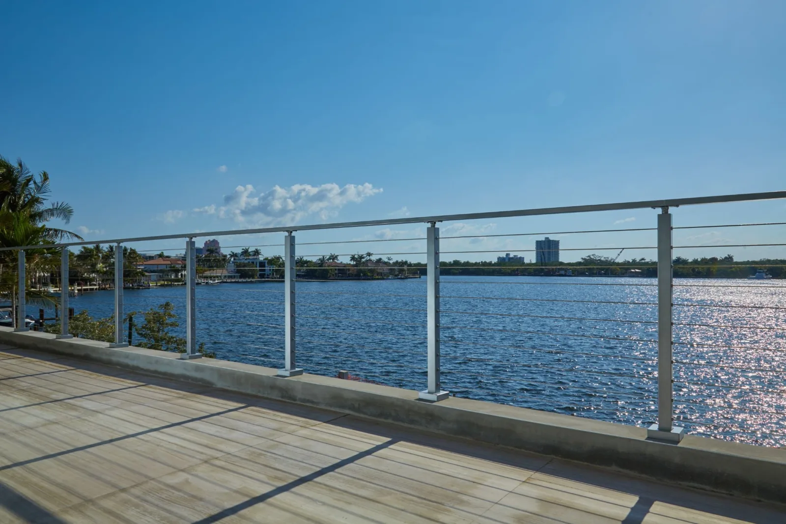 Seawall railing stretching along open water beneath a clear sky