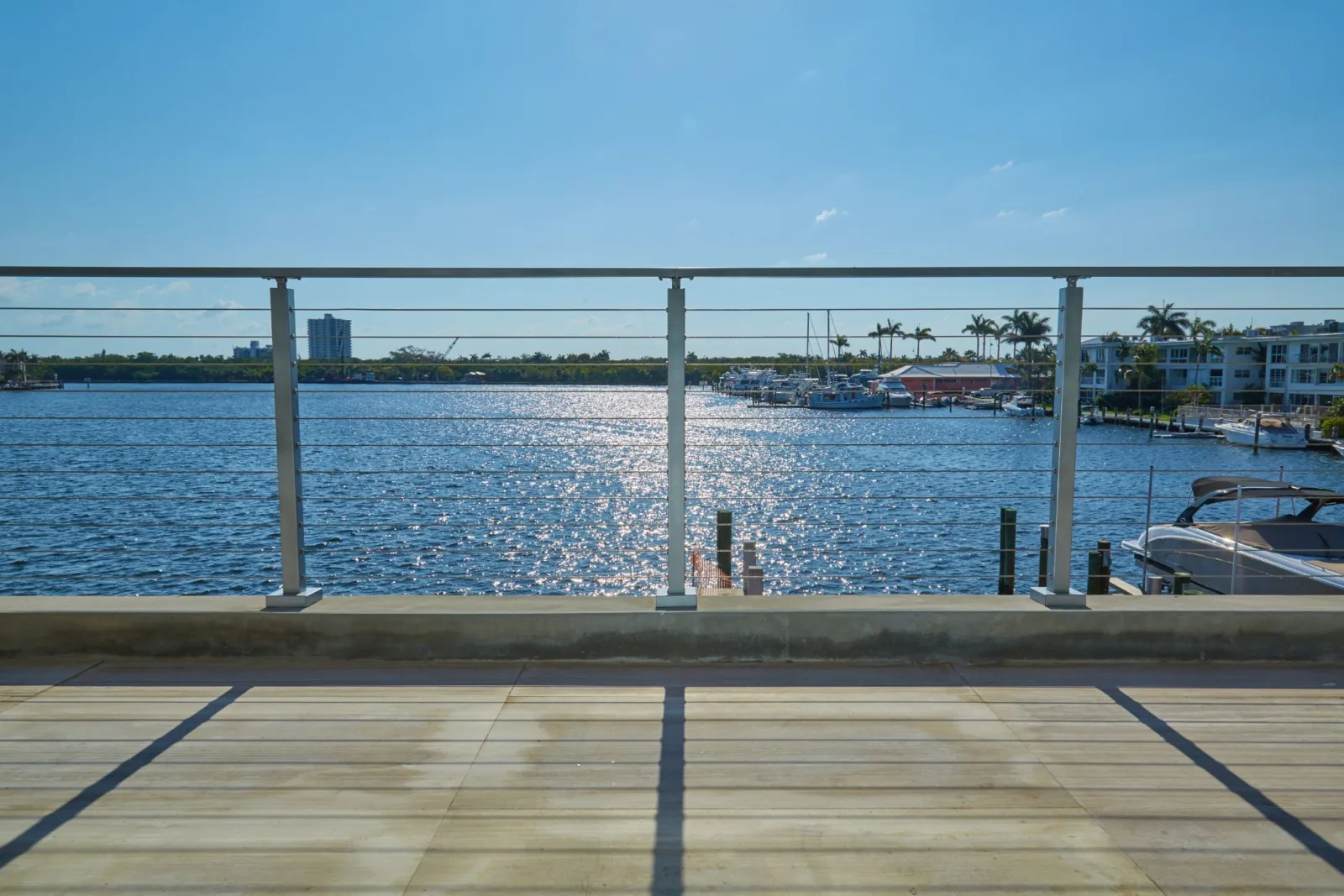 Straight-on railing view over sunlit water from pale wood decking