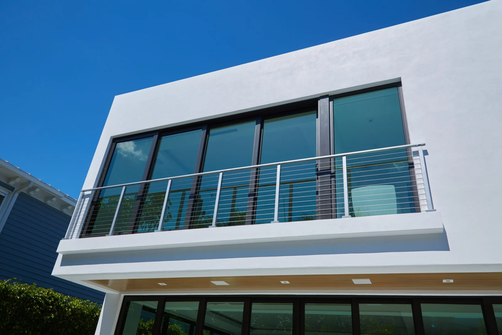 Stainless cable railing on a shallow second-story balcony against a white stucco wall