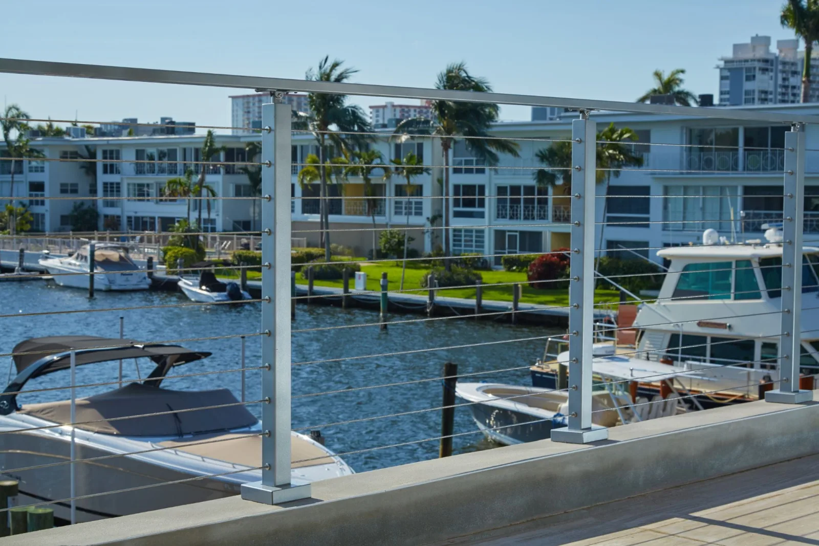 Railing edging a raised patio with yachts moored across the canal