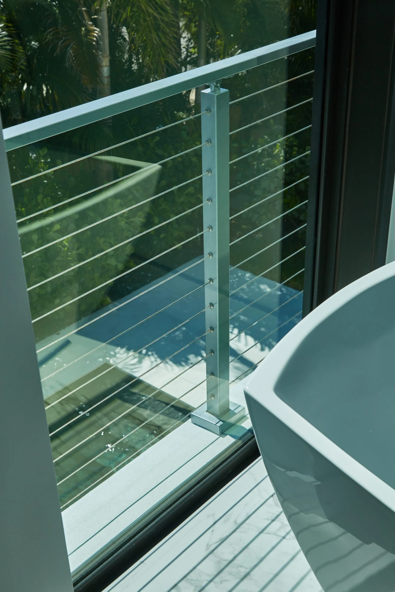 Balcony railing seen through a sliding glass door beside a freestanding tub