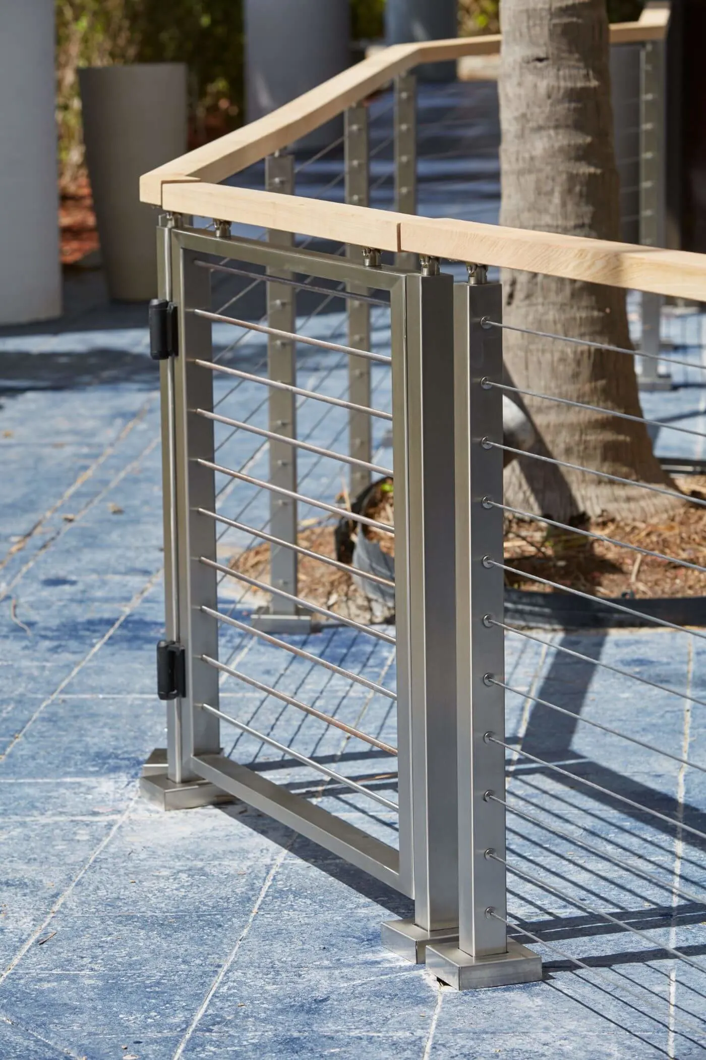 Hinged cable gate with stainless posts and a light wood top rail
