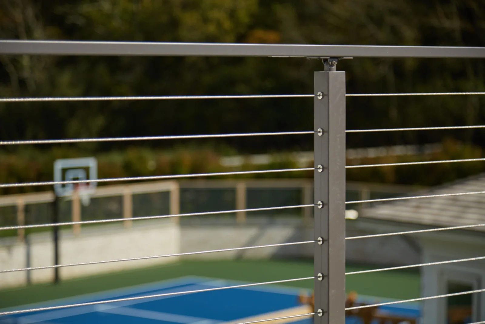 Railing post detail with a basketball hoop and blue court behind