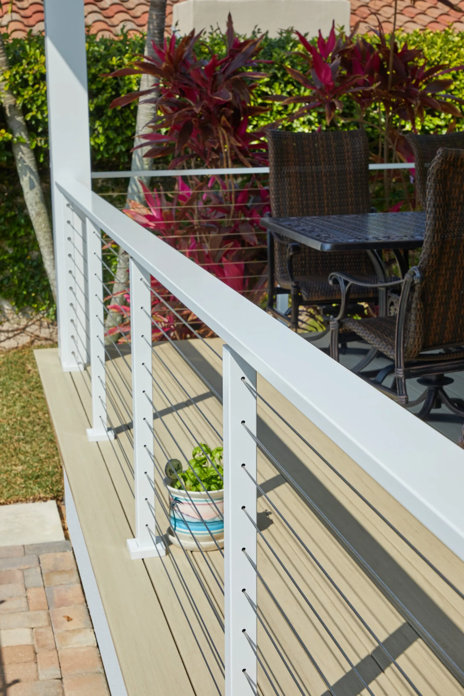 White posts and taut cables edging a deck beside a patio dining set