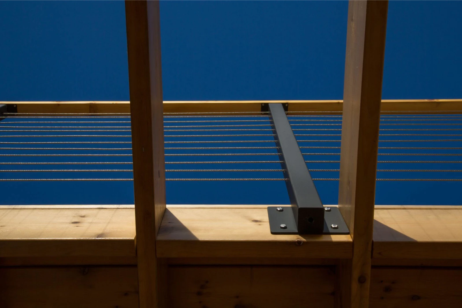 Cable railing and wood top rail seen against clear blue sky from a deck