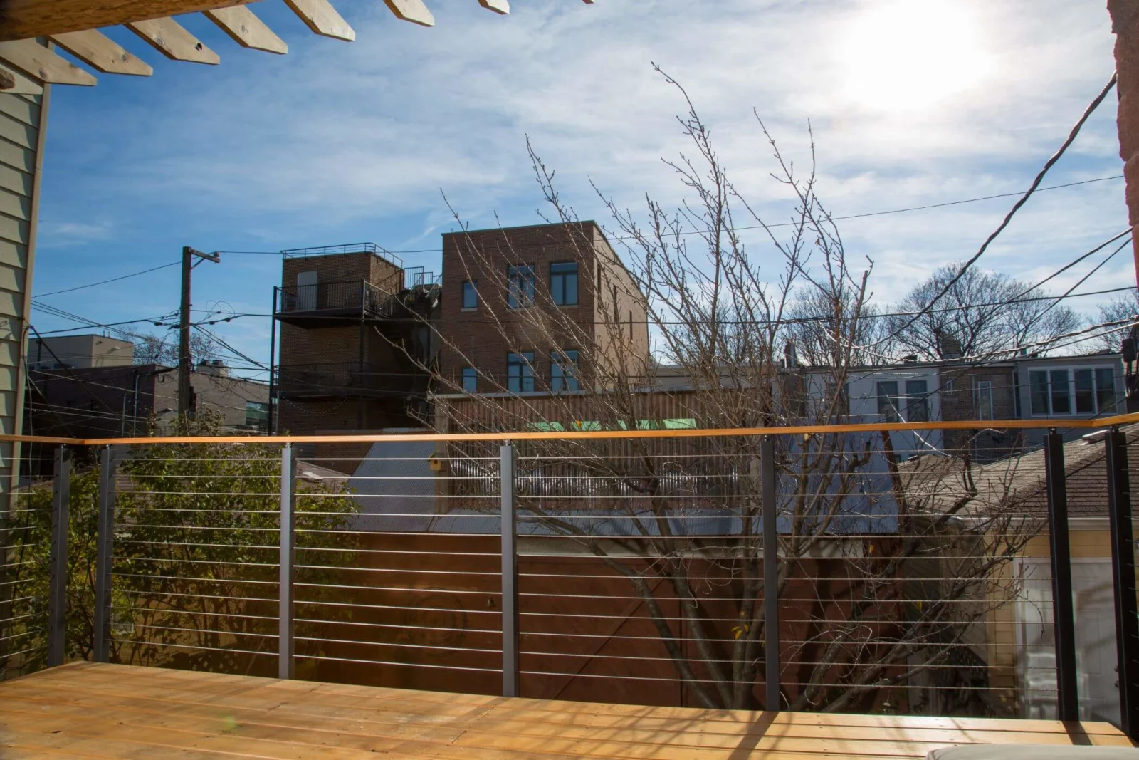 Wide deck view through cable railing toward neighboring buildings and sky