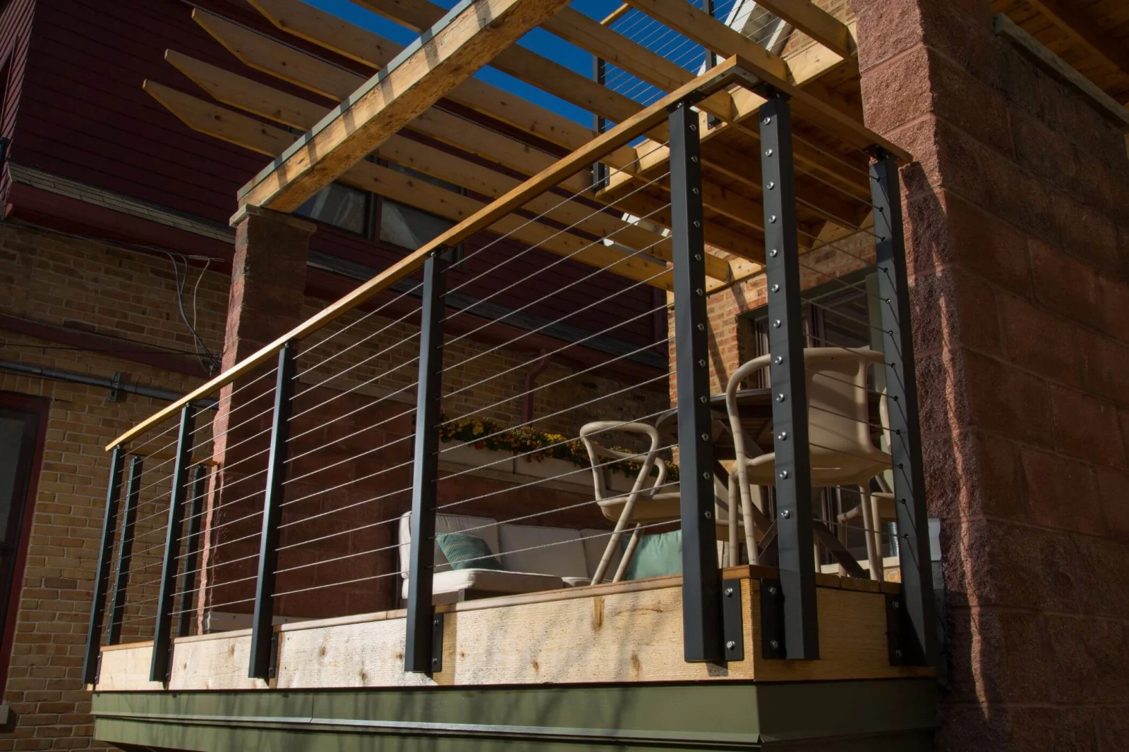 Elevated deck with pergola beams above black posts and tensioned cables