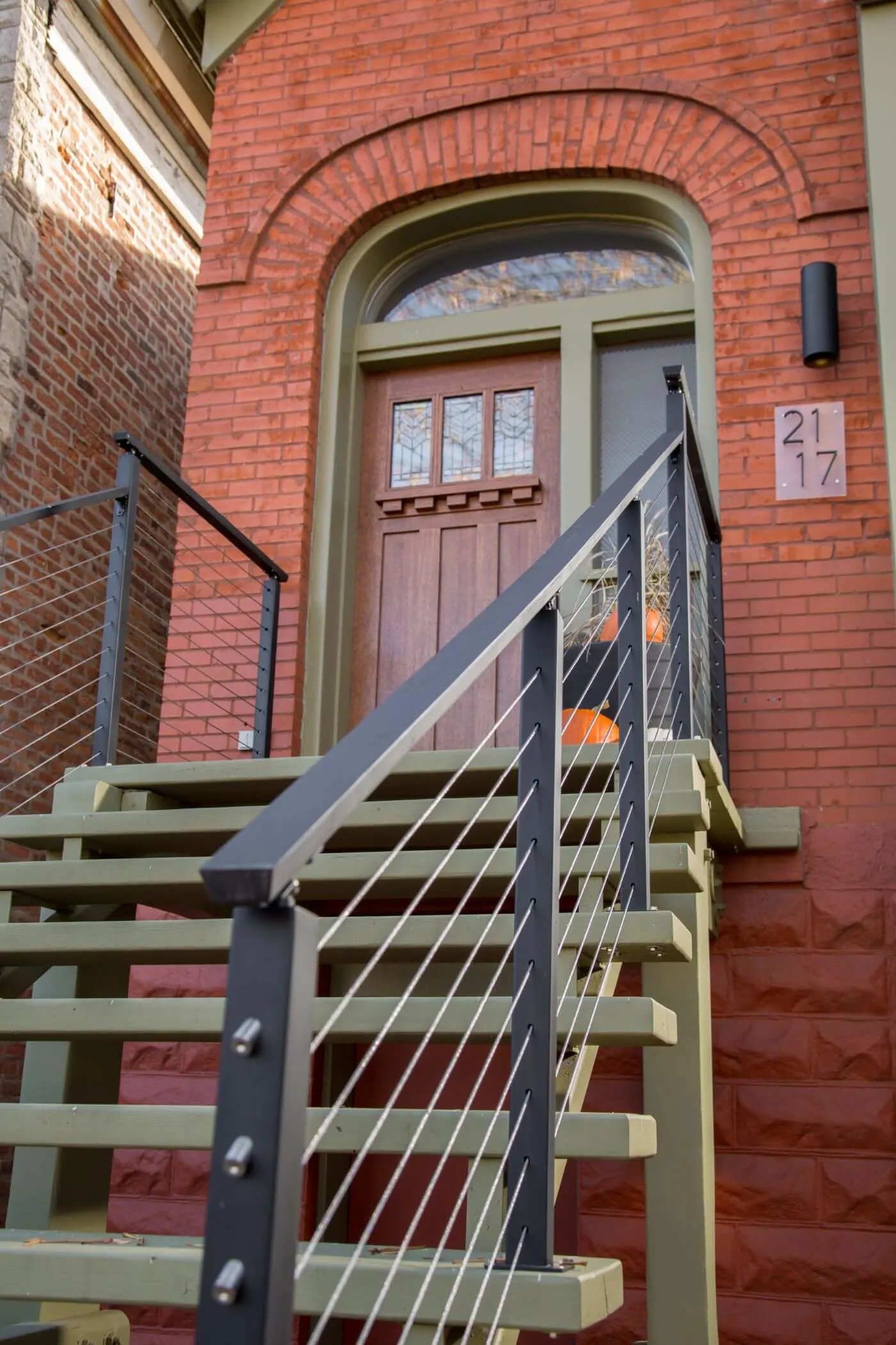 Looking up the entry steps toward an arched doorway framed by cable railing