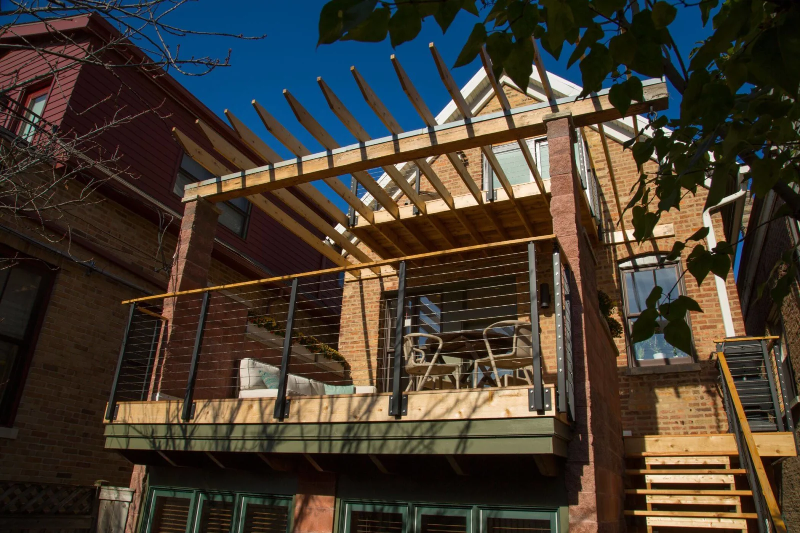 Rear of a brick house with a second-floor deck and cable railing