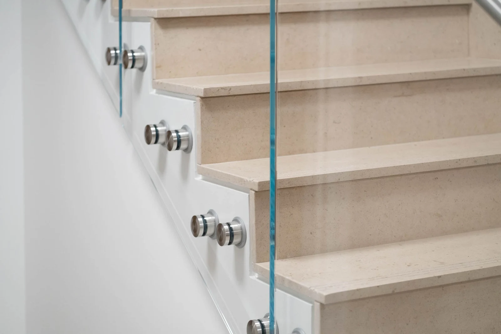 Close view of stone stair nosings behind a glass panel and standoffs