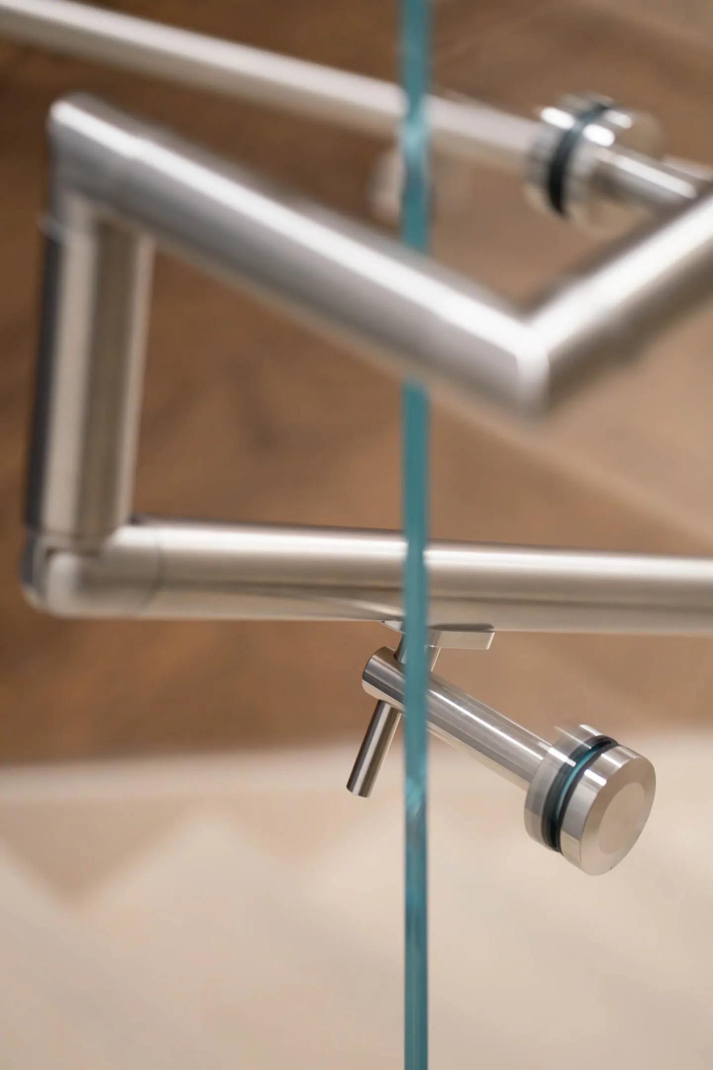Detail of a handrail elbow and its support bracket fixed to glass