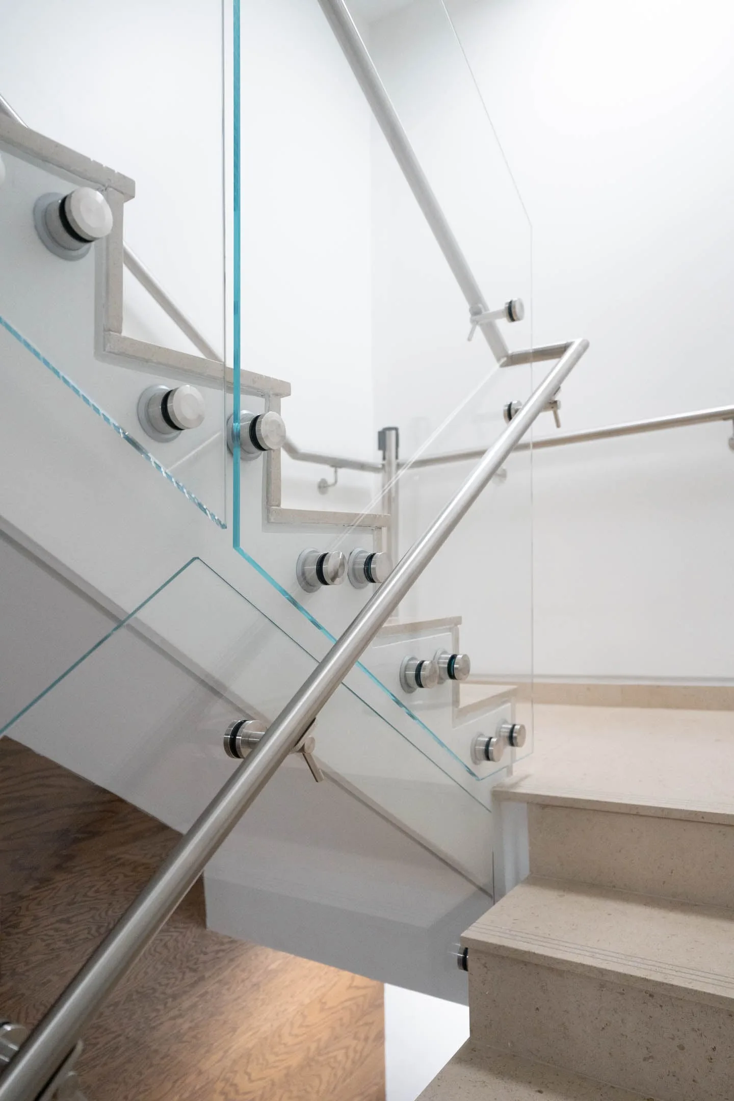Stair landing where glass panels and a stainless handrail change direction