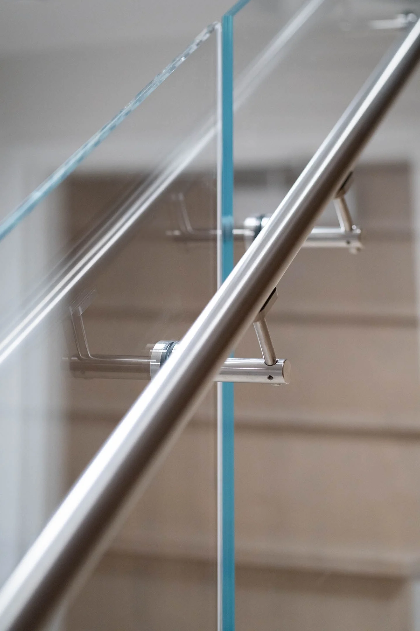 Tight detail of a handrail bracket passing through a glass panel
