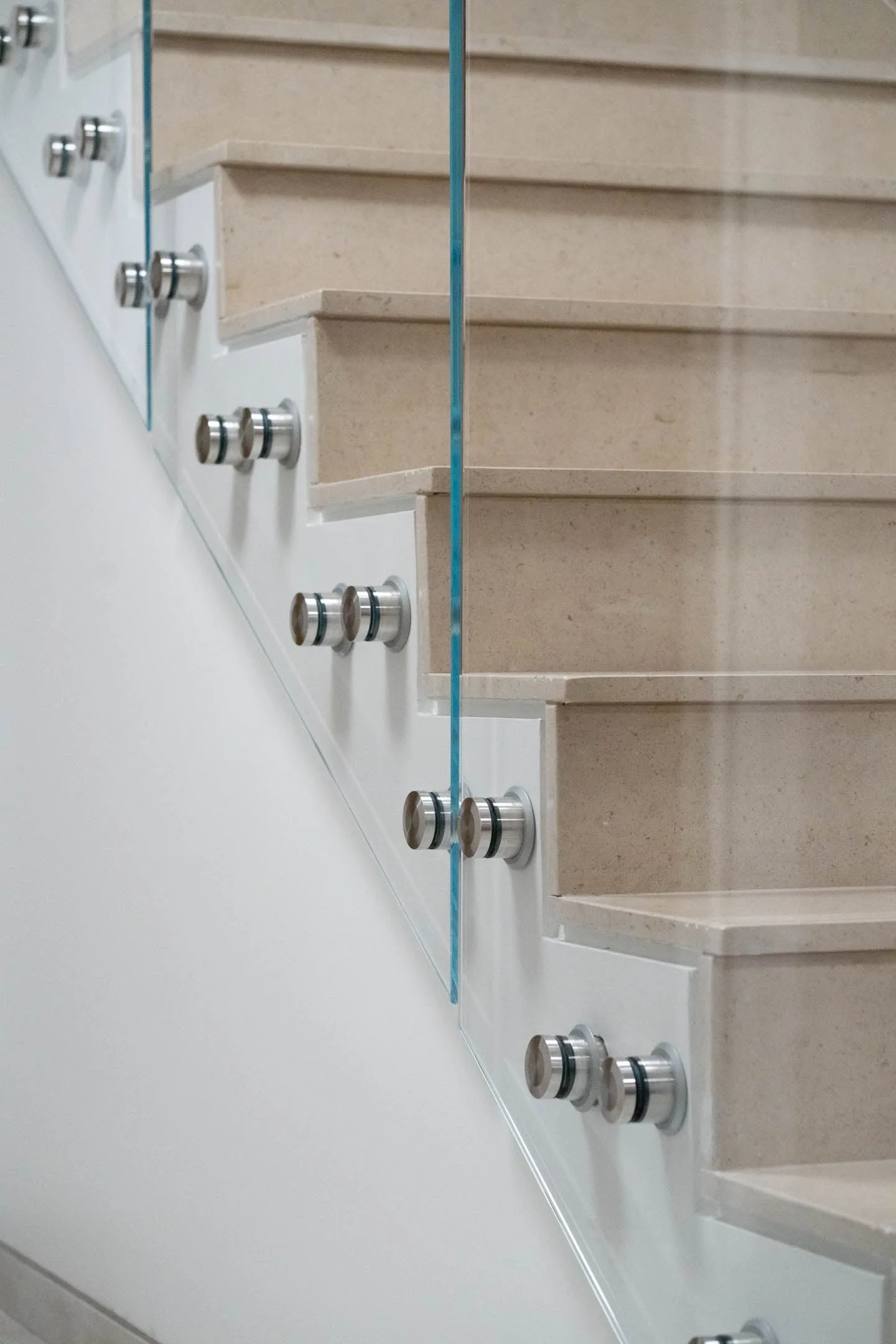 Row of standoff fittings along a white stringer under stone treads