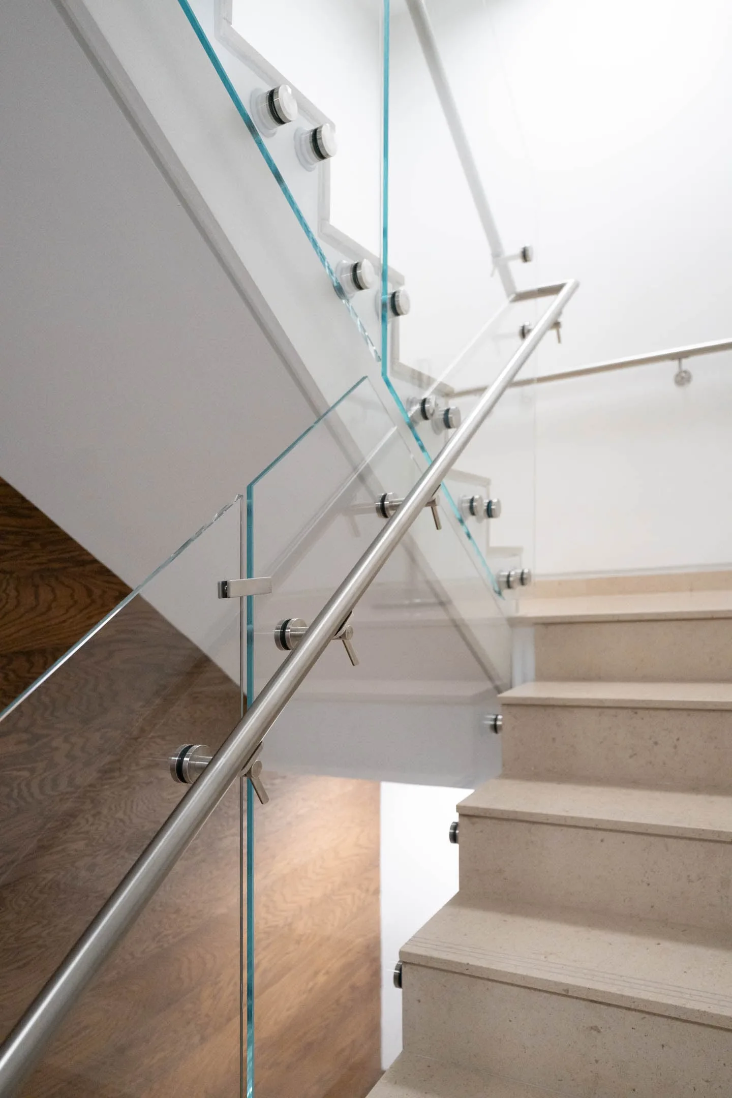 Looking up a flight of stone stairs framed by glass and stainless handrail