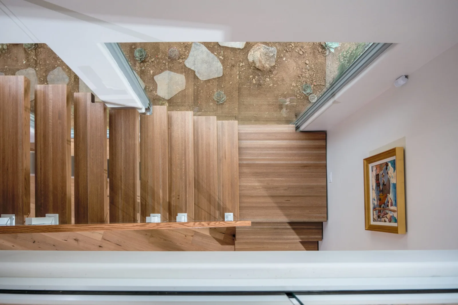 Looking down the flight at wood treads and glass panel standoffs