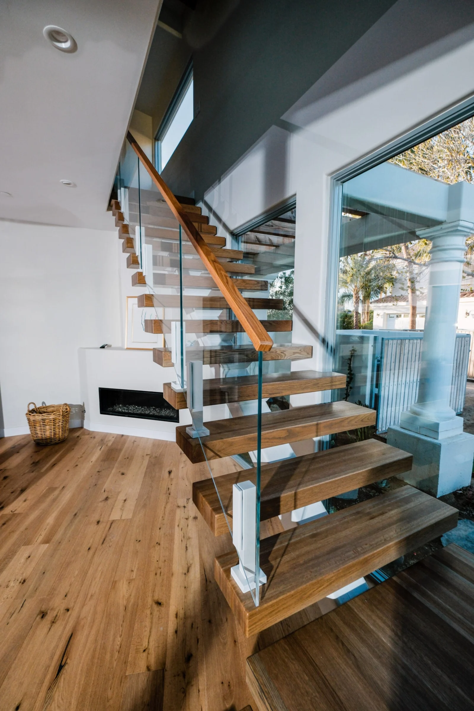 Floating stair on a white stringer with wood treads and glass railing