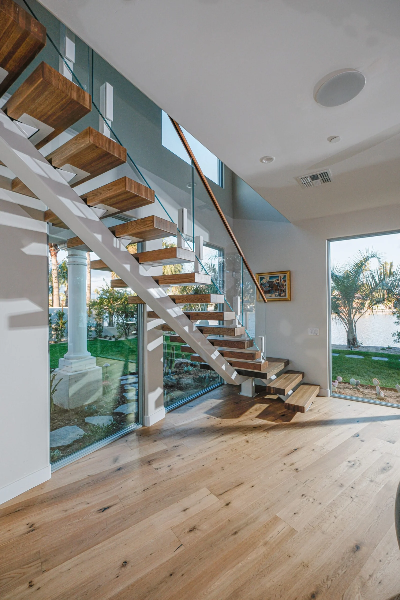 Room view of the white-stringer stair against a wall of garden glass