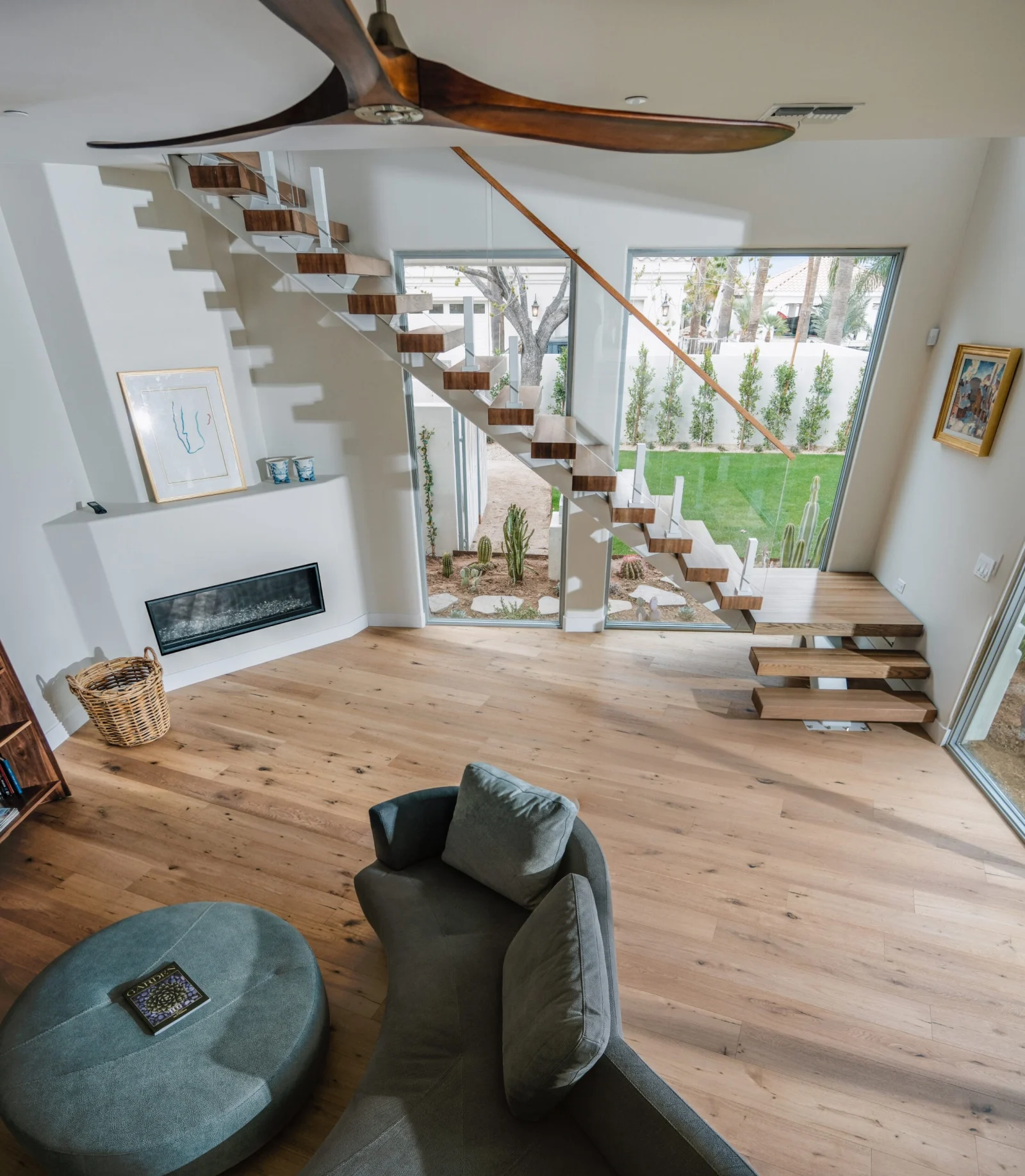 Living room with fan blades overhead and the stair beyond a linear fireplace