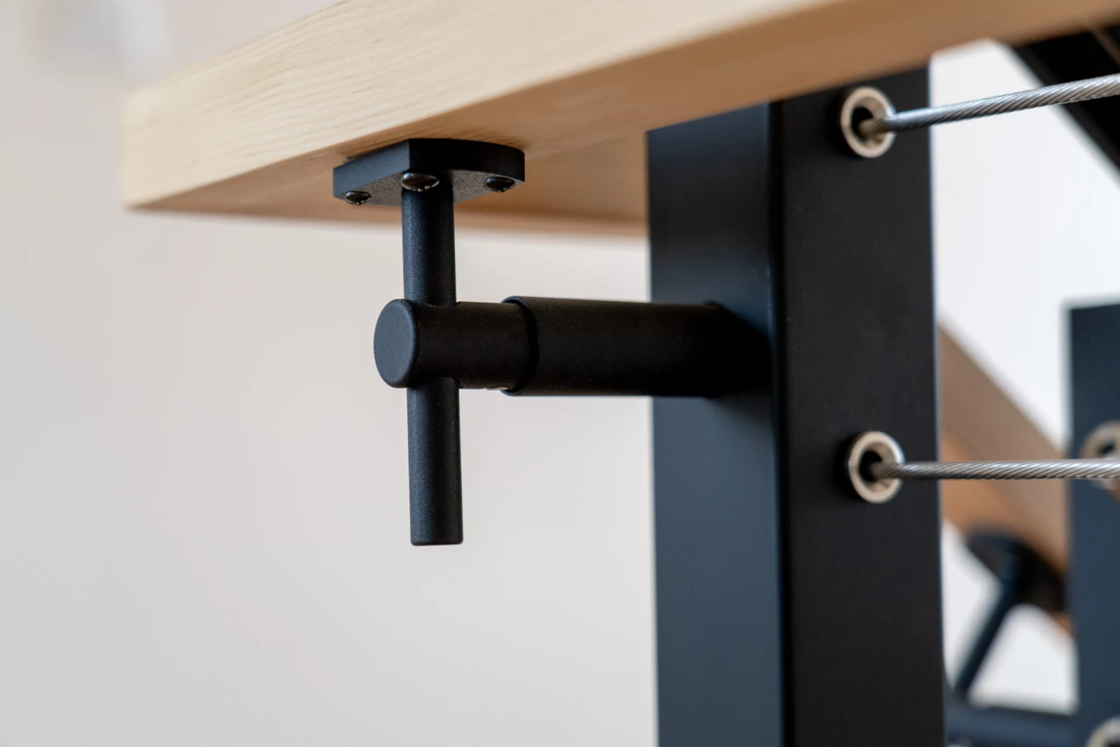 Detail of a black handrail bracket under a light wood top rail