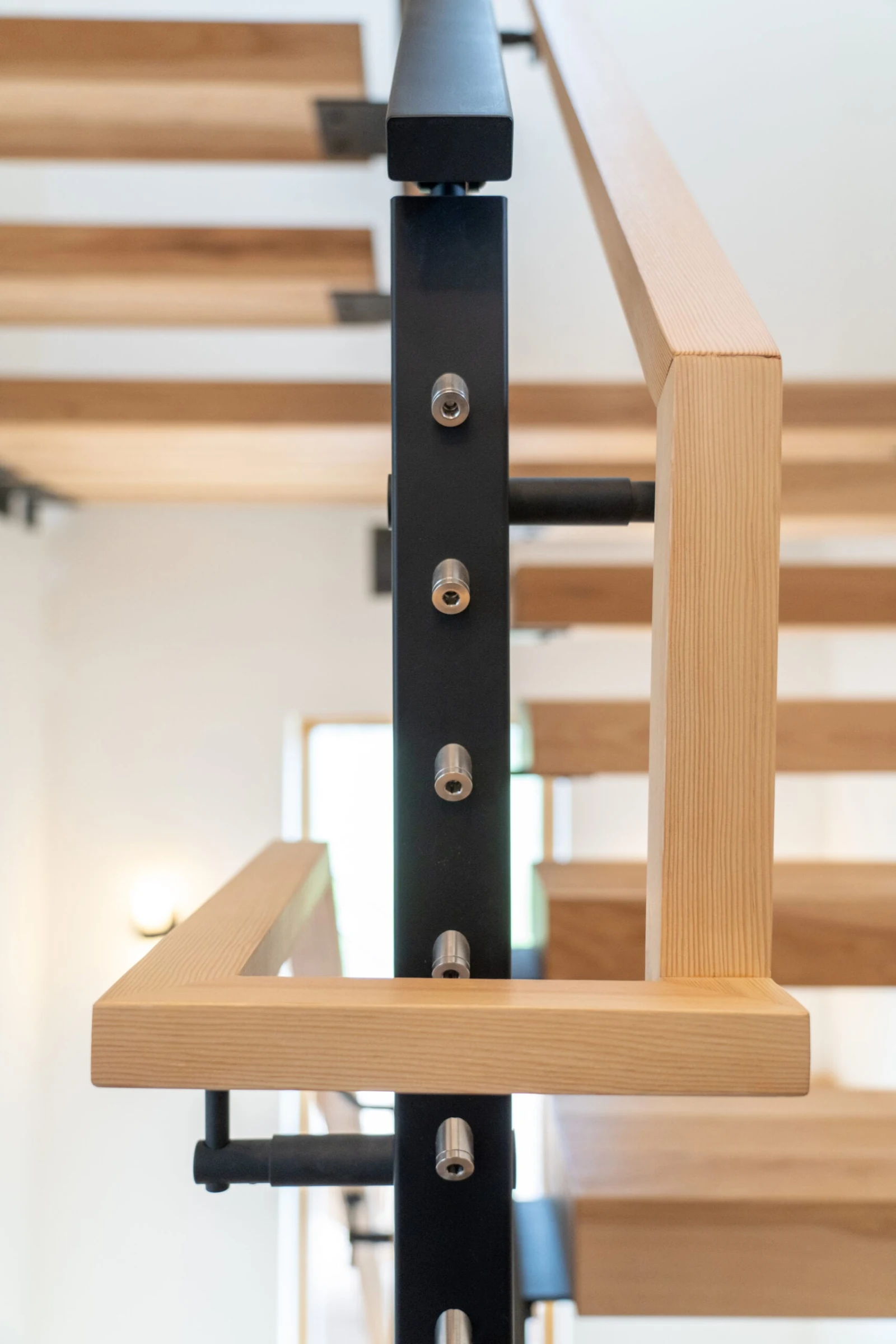 Black post with cable fittings beside a wood handrail and open treads