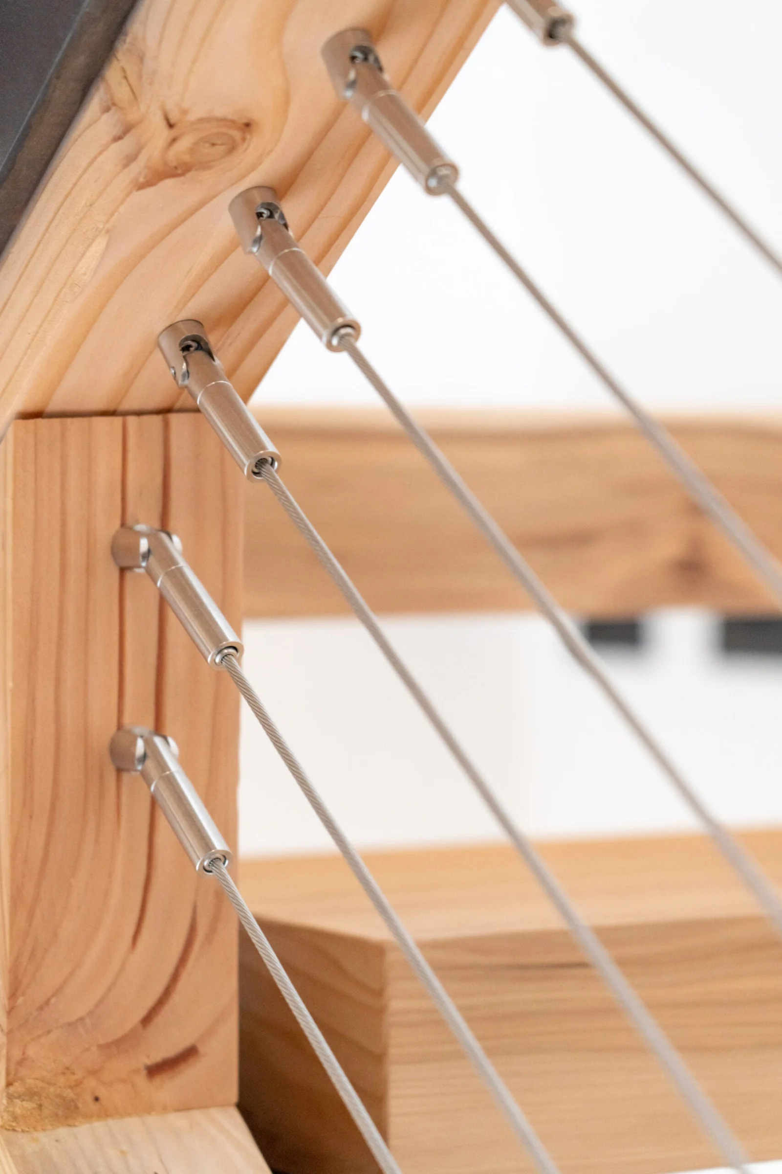 Close view of cable fittings anchored into a light wood stair stringer