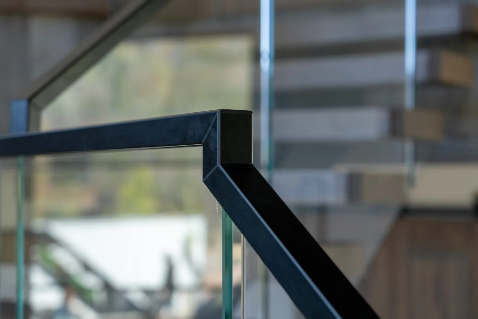 Close view of the mitered black top rail corner capping frameless glass panels