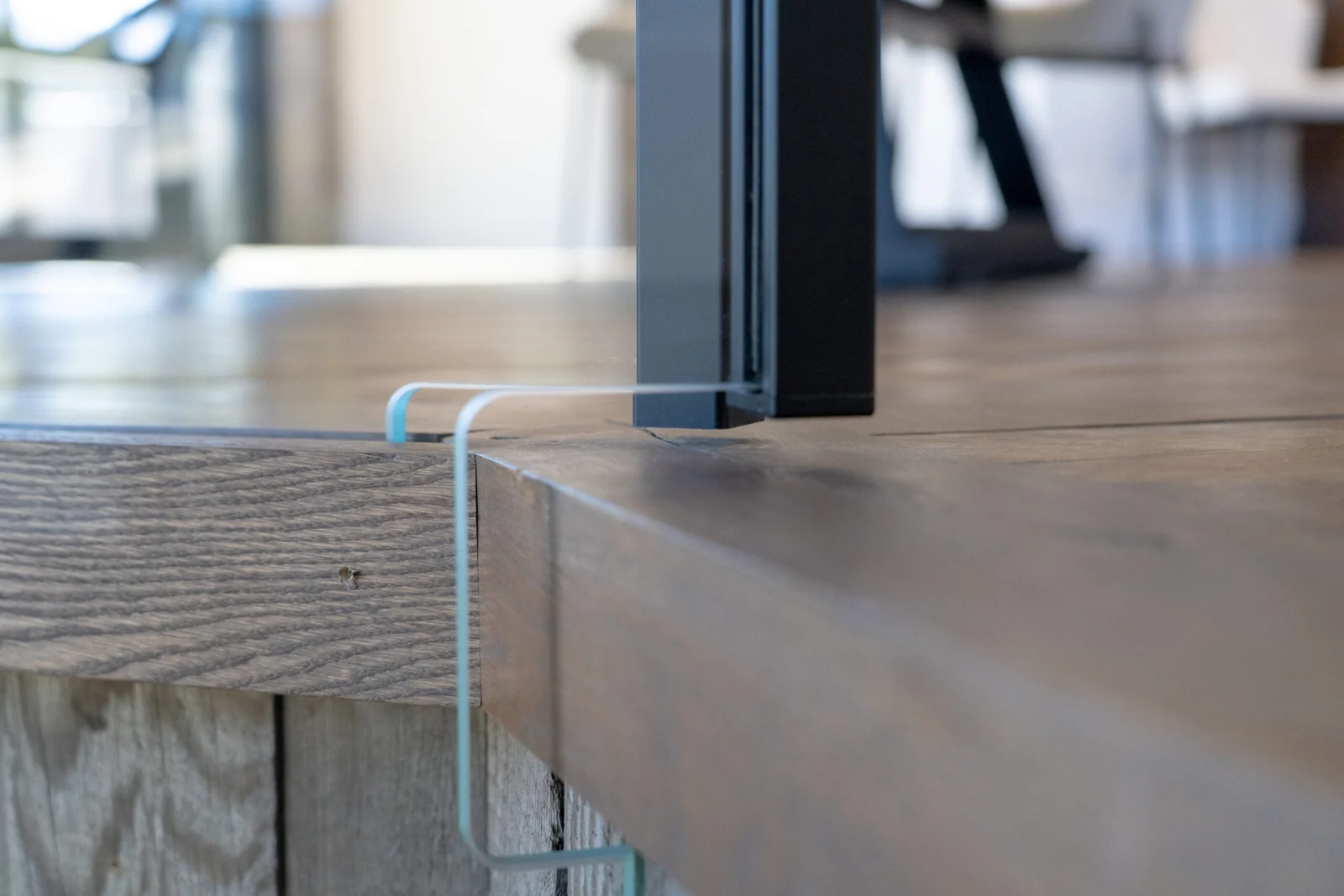 Base detail where a glass panel meets the wood landing edge beside a black post
