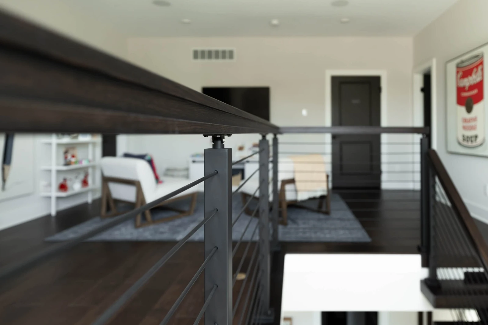 Low angle along the wood top rail of a balcony run above an open family room