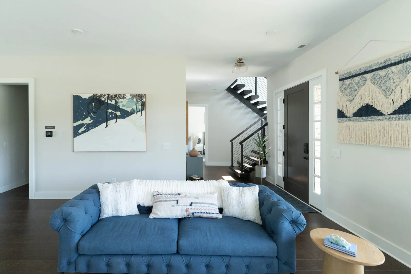 Living room with tufted blue sofa and the stair rising in the background