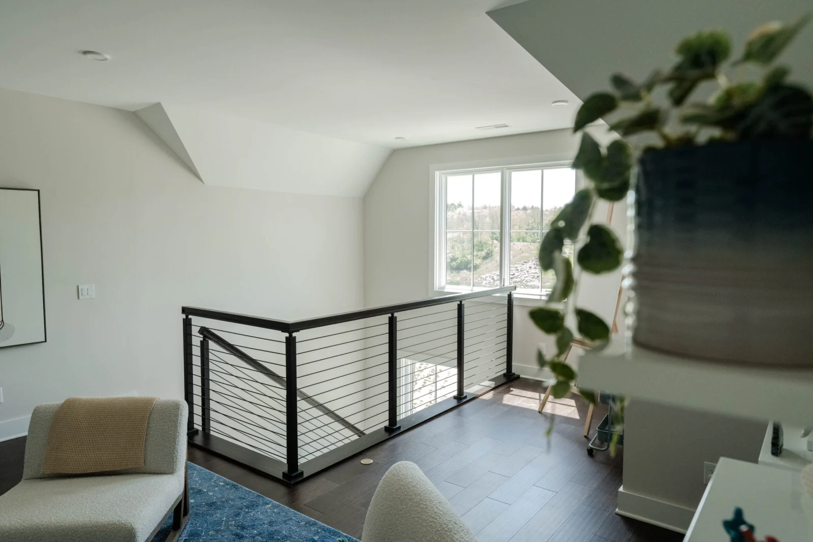 Sitting room overlook framed by a black rod railing run below a sloped ceiling