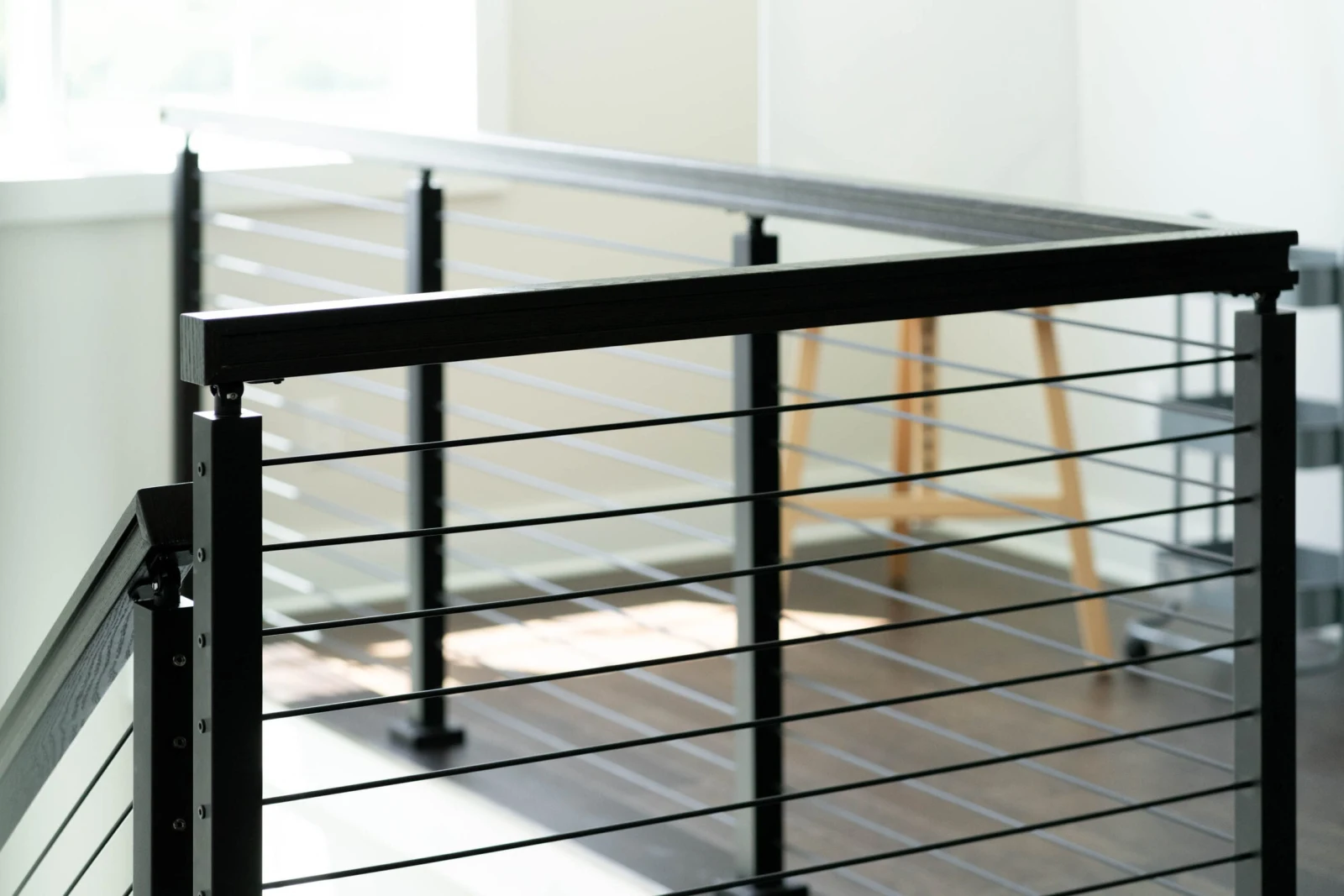 Corner detail of black posts, top rail and evenly spaced horizontal rods